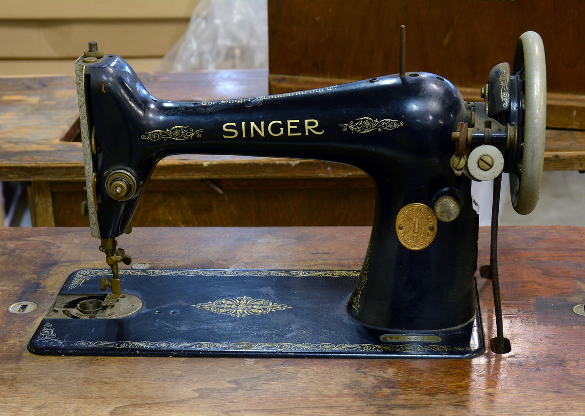 Symaskin merke Singer, med lokk av tre og med bord i smijern.