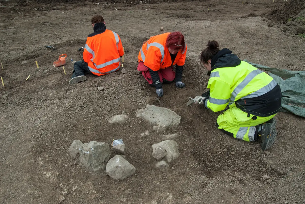 Utgrävning av kistbegravningar på gravgården vid Broby bro. Arkeolog Jennifer Shutzberg från Stockholms läns museum (gul väst) samt studenter från Stockholms universitet.