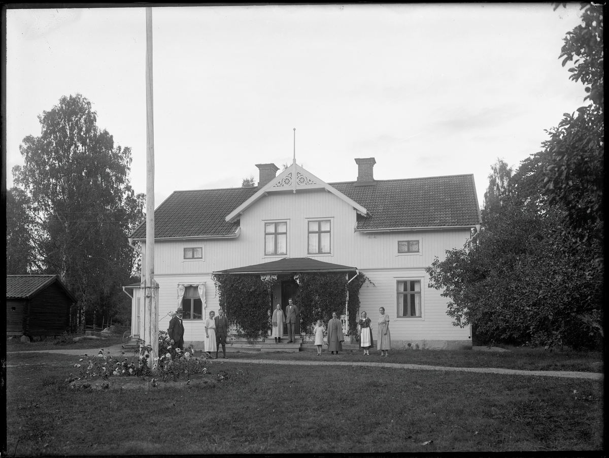 Grupporträtt framför hus. G. Olsson, Bärsta, Kolbäck 
Ur Gustaf Åhmans samling.
