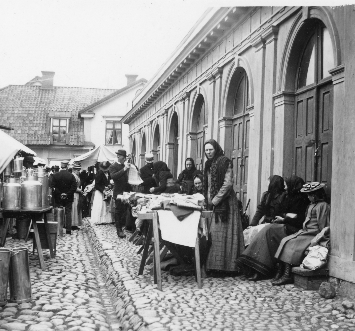Torghandel på Hospitalstorget i Linköping. Fotografen hade placerat sig invid basarlängan utmed torgets östra sida. Odaterad bild från tiden omkring år 1900.