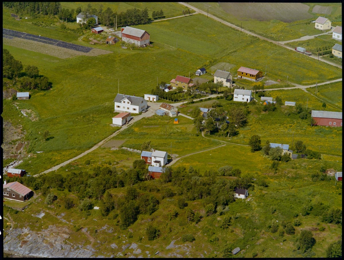 Leirfjord,Leland. Flyfoto fra område ved Breivika. På bildet ser en det som var meieri på Leland, og som også har vært kommunehus og bibliotek. Til høyre i bildet sees fjøset til gården "Nerhåjen".