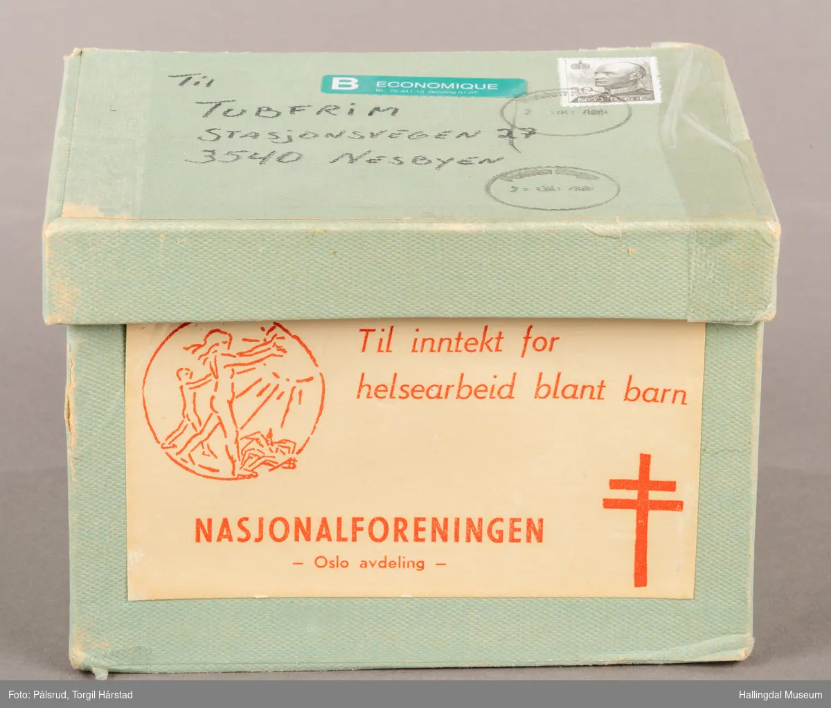 Samleeske i papp, for innsamling av frimerker til Nasjonalforeningen for folkehelse / Tubfrim. Boksen har et "henglset" lokk som sitter fast på den ene langsiden. Den er trekt i et lyst turkis papir. På lokket står det adressen til Tubfrim med et stemplet frimerke fra 1992 av Kong Harald V.