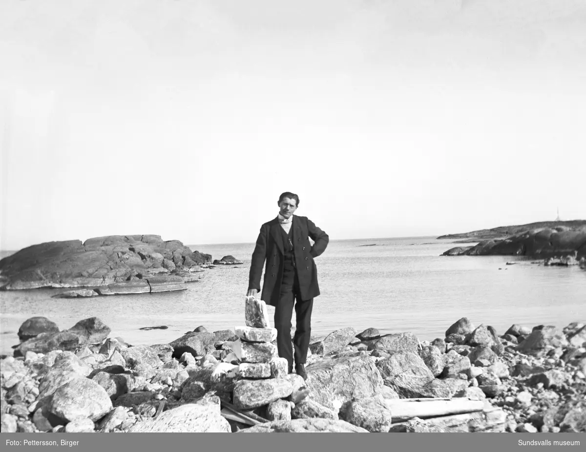 Skärgårdsvy med en man som står på klipporna i förgrunden.