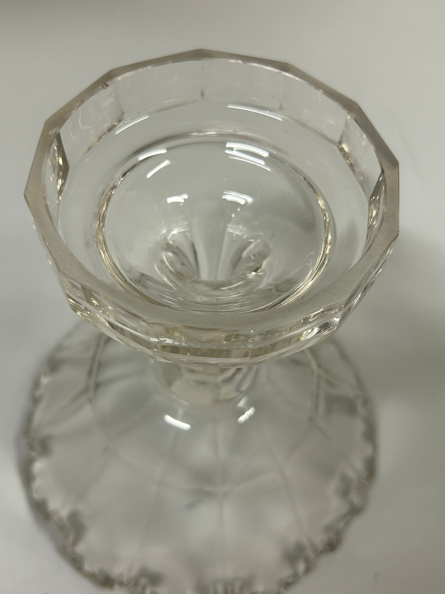 Tolvkantig skål av ofärgat glas på högt ben. Mynningskanten är fasettslipad och uddformad. Lambrequinform.
