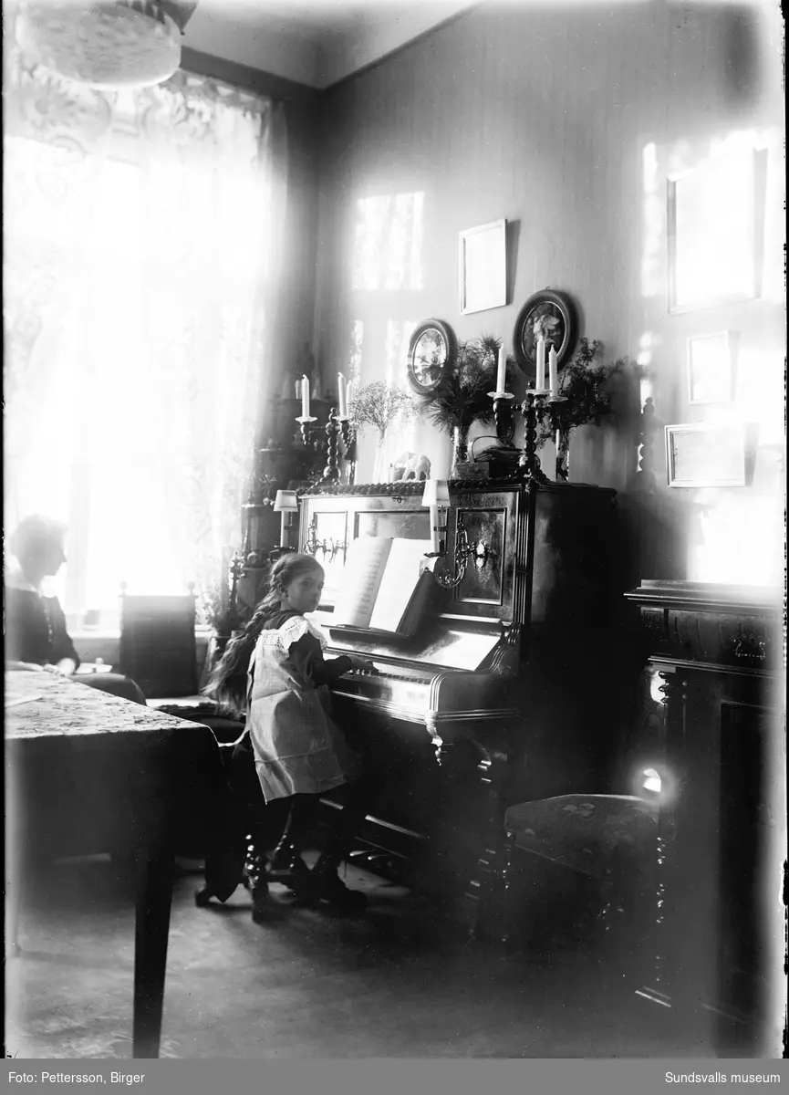 En flicka sitter och spelar piano och en kvinna sitter bredvid. Två bilder från olika tillfällen men med samma rum och personer.