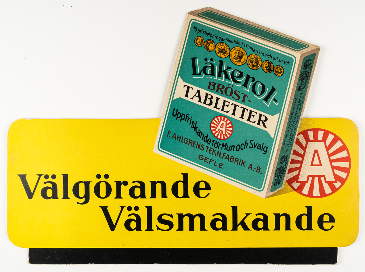 Reklamskylt i papp, ställbar. Gul med svart text och en grön Läkerolask. Reklamtext "Välgörande Välsmakande". Handskrivet på baksidan "1932".