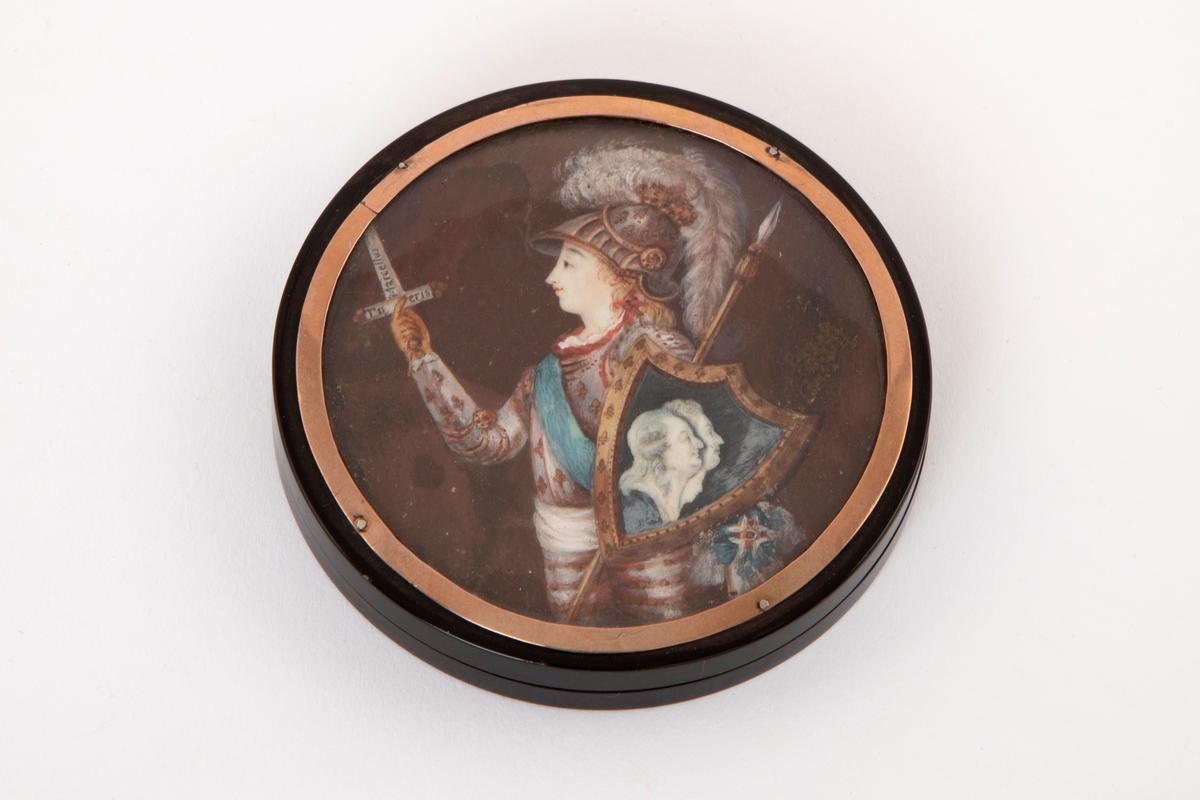 Rund, flat dåse av horn med løst lokk. På lokket under glass et minitayportrett av en ung krigskledd mann med skjold, hvori to portrettprofiler.