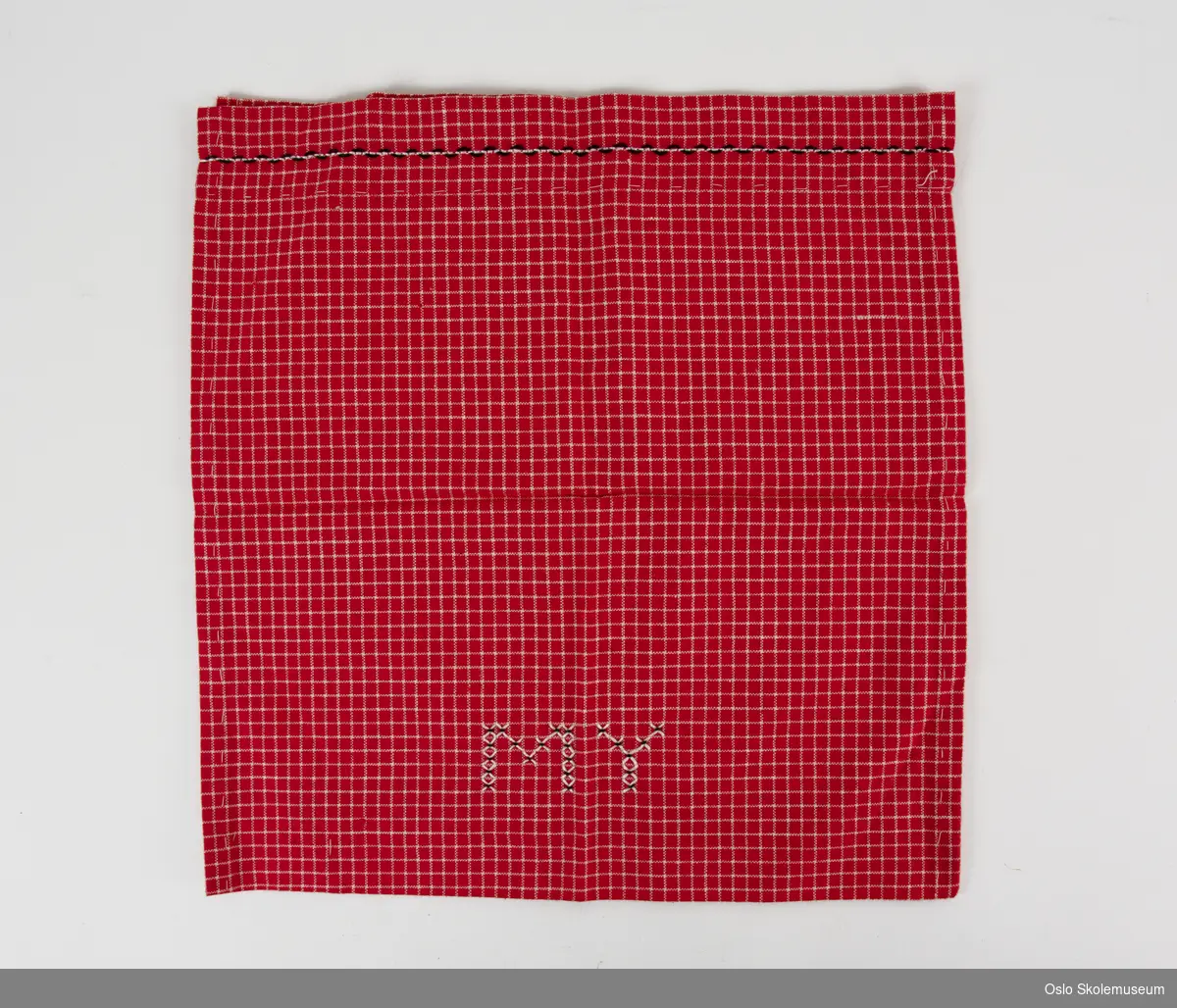 Gympose i rød tekstil. På fremsiden er det brodert "MY" i hvitt og svart. Posen er ikke ferdig sydd.