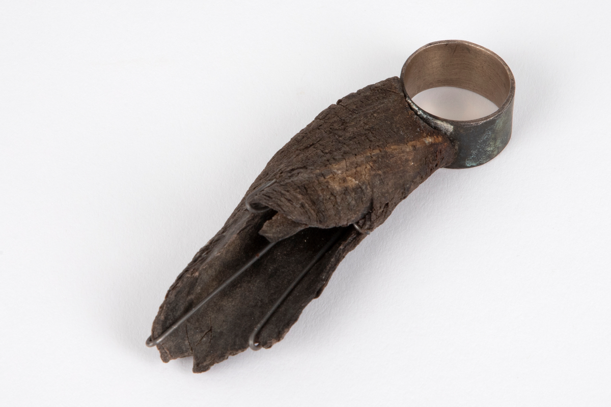 Sølvring med horn. Sølvet er oksidert på utsiden og har delvis en grønn patina. Hornbiten er festet til ringen med fire klammer. Ringen er uten signatur.