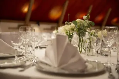 Et borde dekket med hvite servietter og blomster. 