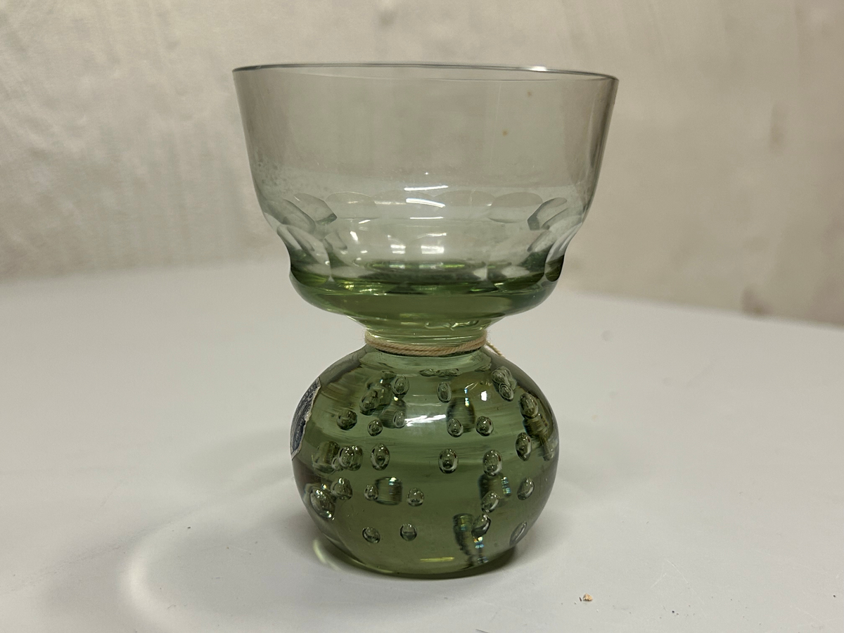 Dricksglas med gröntonat glas. Klotformad fot med luftblåsor. Kupa med olivslipad dekorbård.