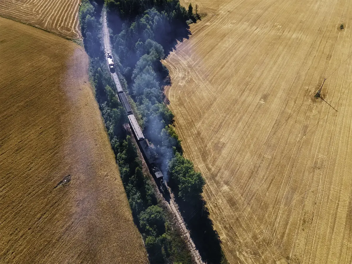Bilde tatt fra drone: et damplokomotiv kjører mellom to åkre.
