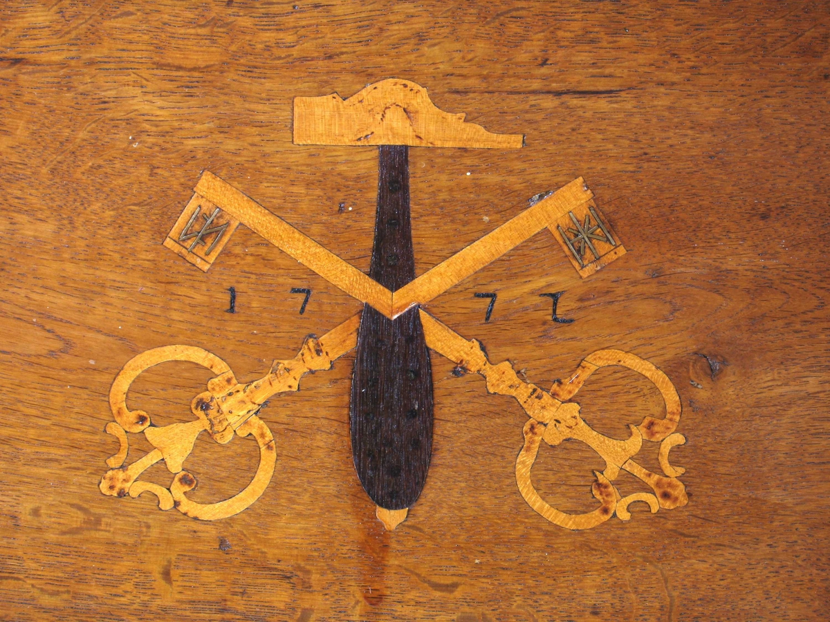 På skrinets forside en hammer med to korslagte nøkler i intarsia og  årstallet 1772.