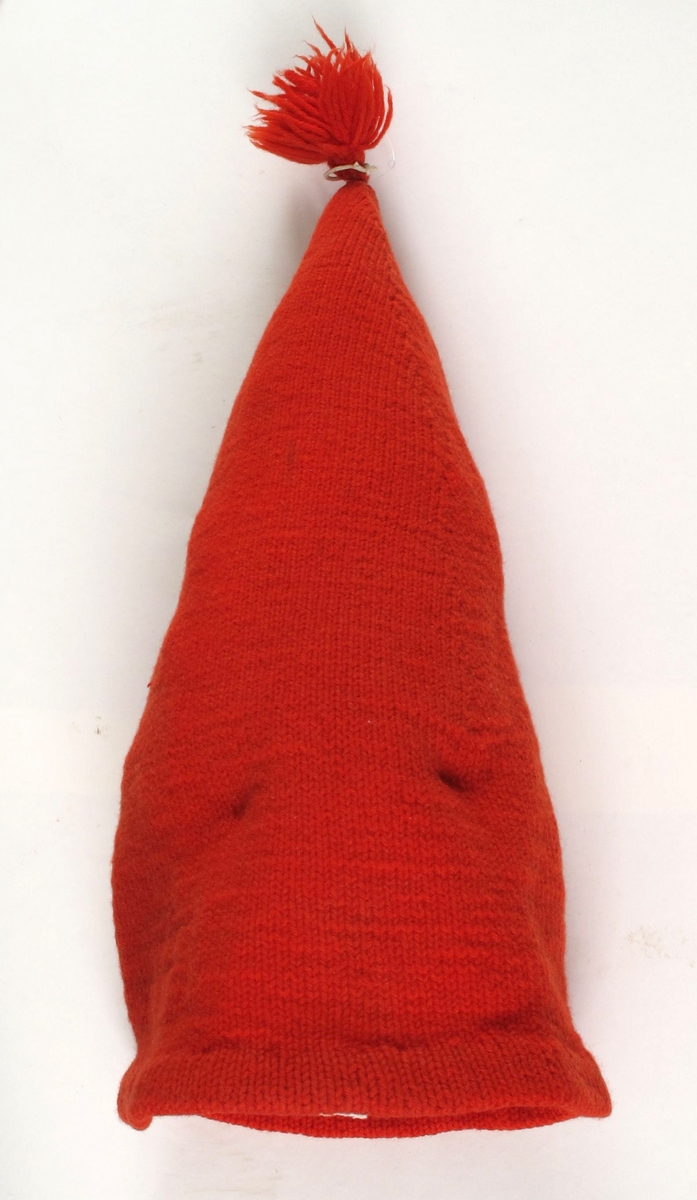 Nisselue, rød topplue.  Ull, rød,  strikket. 
 Barnetopplue,  forholdsvis lang og spiss.  Oppbrettet/fald sydd til med rød tråd.  To rader med fellinger.