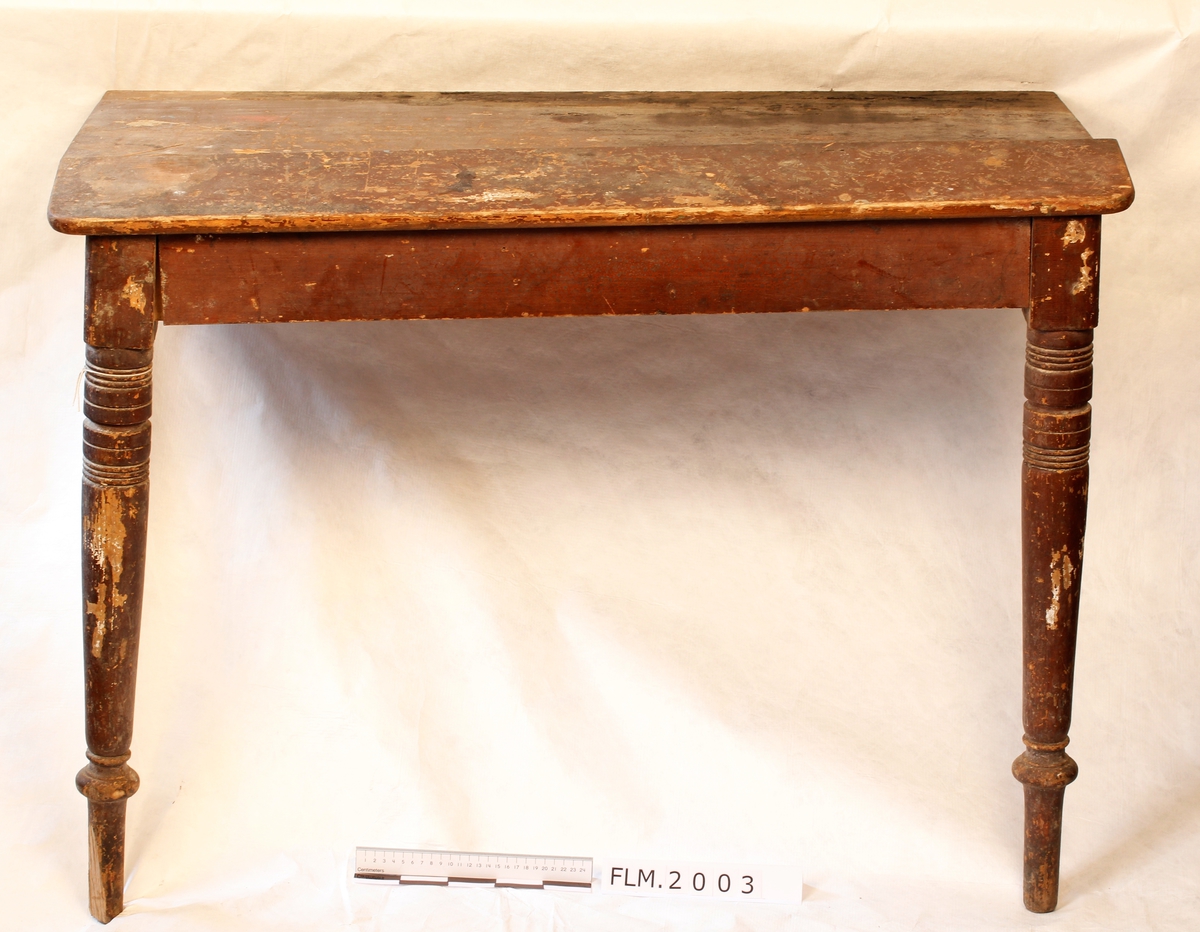 Arbeidsbord som tidligere stått på utstilling i Trådbua.  Har troligen vært brukt på Fetsund Lenser. Bordet er laget slikt at det kan demonteres. 

Mangler to bein og en side.