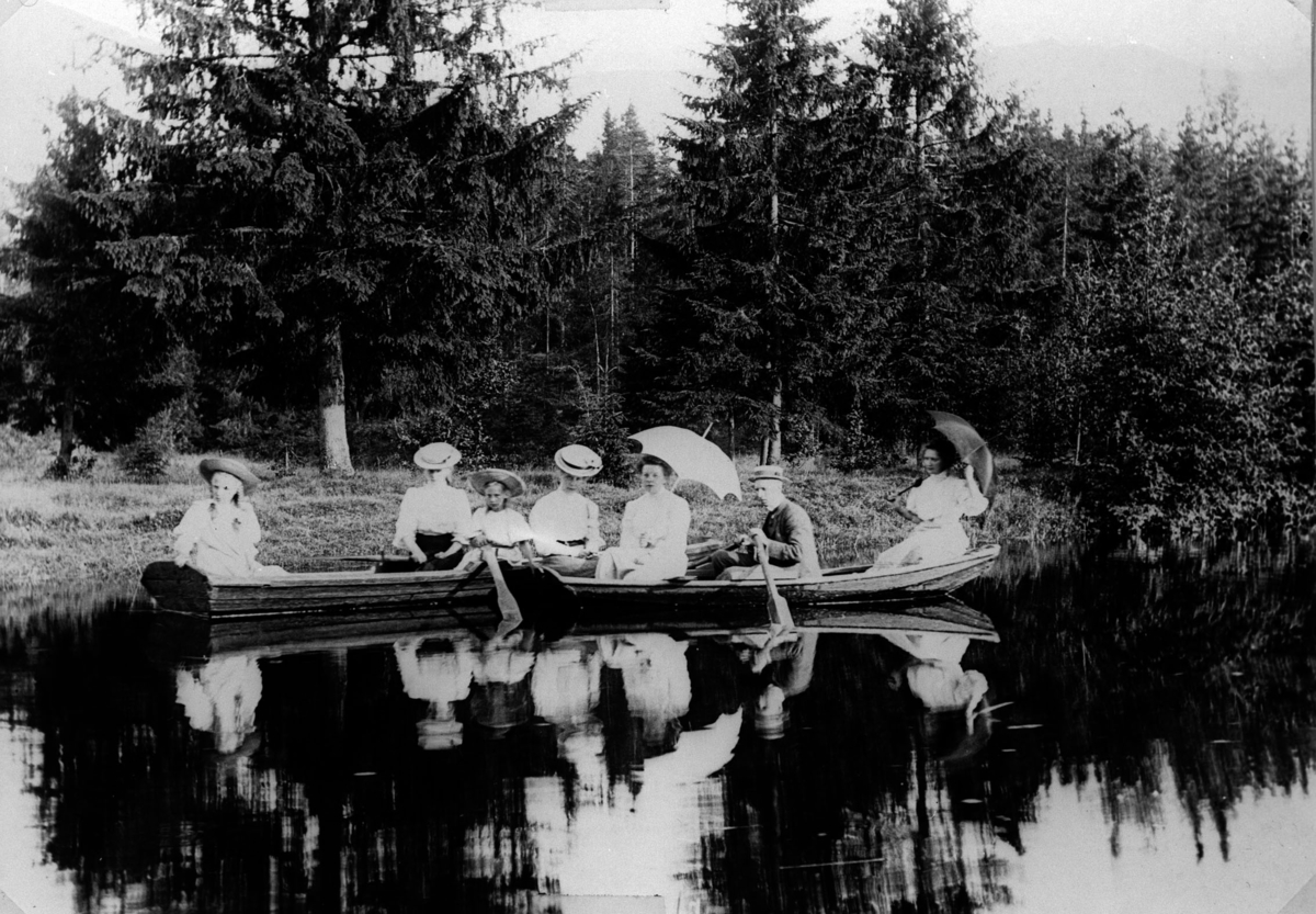 3 kvinner, 2 barn, 1 mann som ror en flatbunnet pram på et vann