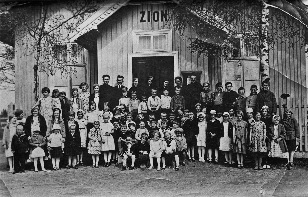 Barn og voksne utenfor menighetshuset ZION.
