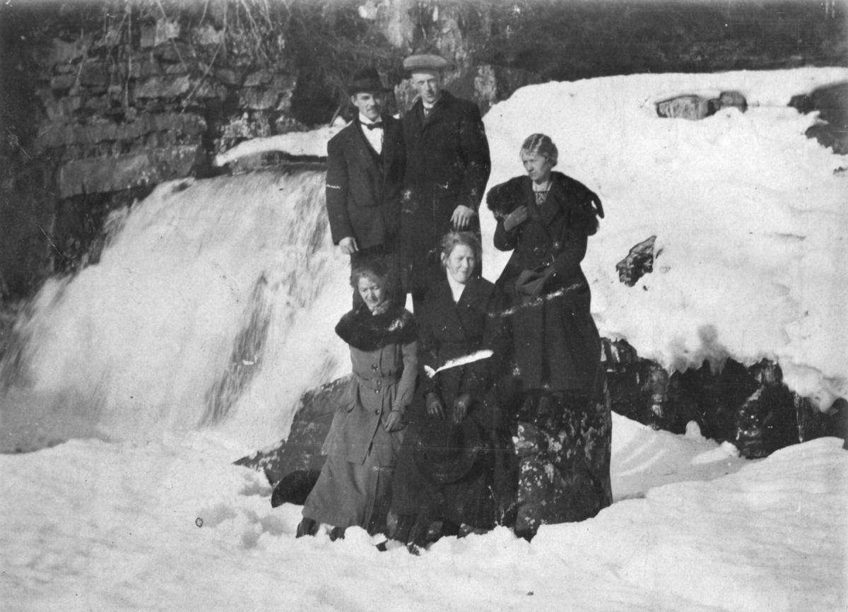 Gruppe 5 menn, kvinner på tur ved foss, vinter