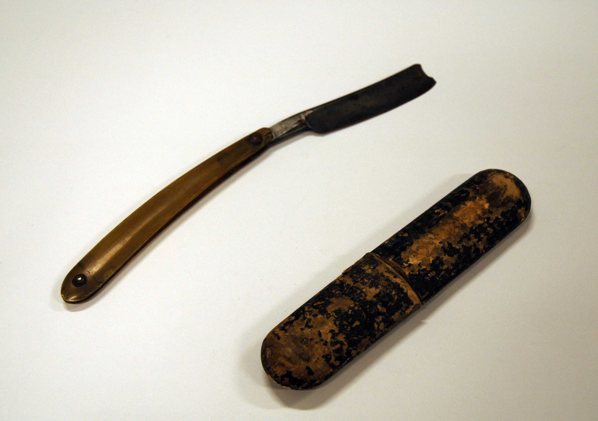 Sammenfoldbar barberkniv med hånd del av horn og en kniv del av jern. Sammen foldet puttes den i et pappetui.