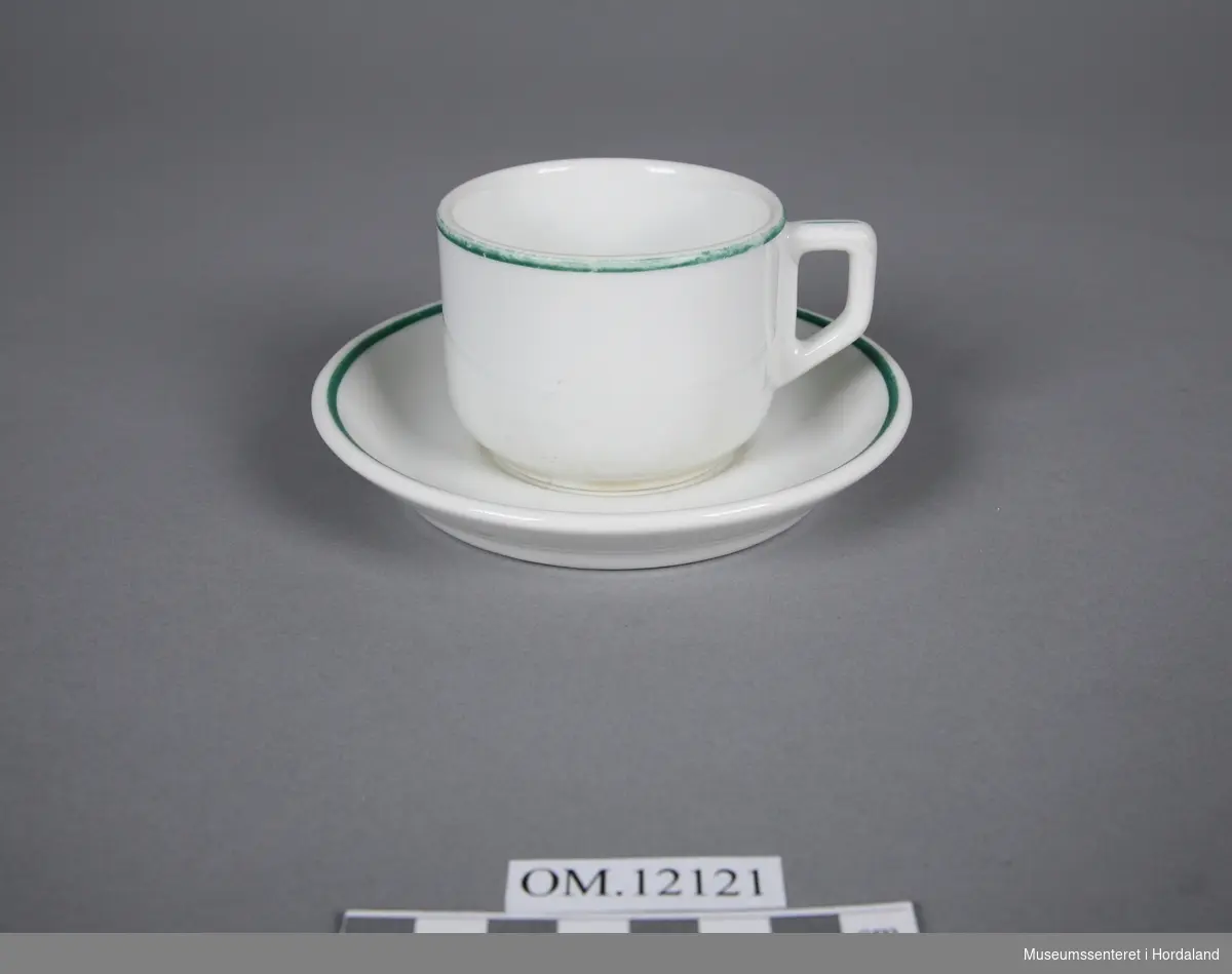 Servise består av 2 koppar og 2 tefat. Gråkvitt og rettlinja, med grøn kant på kopp, hank og på fat.
