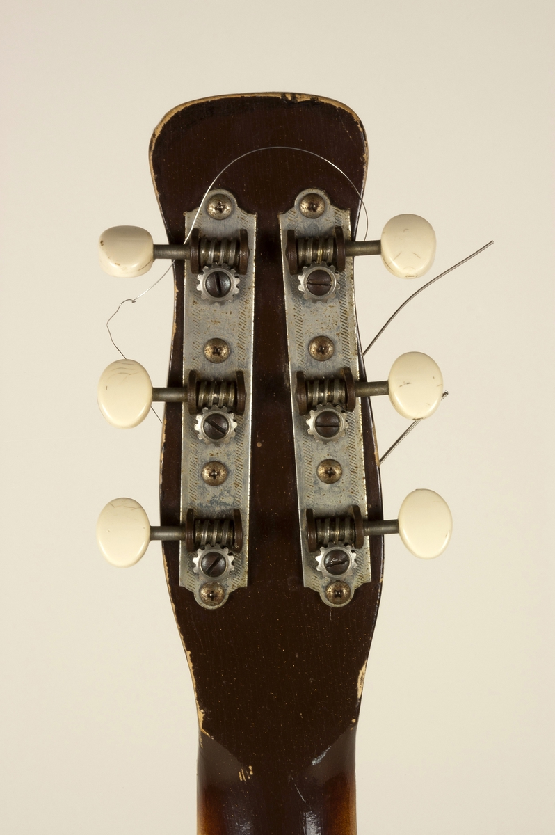 Elektrisk gitar (semi-hollow) med kropp av masonitt og furu, brunlakkert med en "sparkling finish" av metallic gull. Enkel cutaway. Hals av poppel. gripebrett av rosentre.  En enkel pickup, såkalt "lipstick". På grunn av formen på gitarhodet refereres den ofte til som "Coke-bottle headstock".