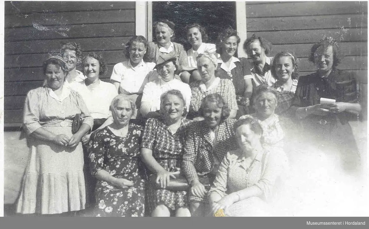 Gruppebilete av kvinner. husvegg.