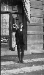 Gutt i uniform fra Grand Hotell foran kafé. Freia Melkechoco