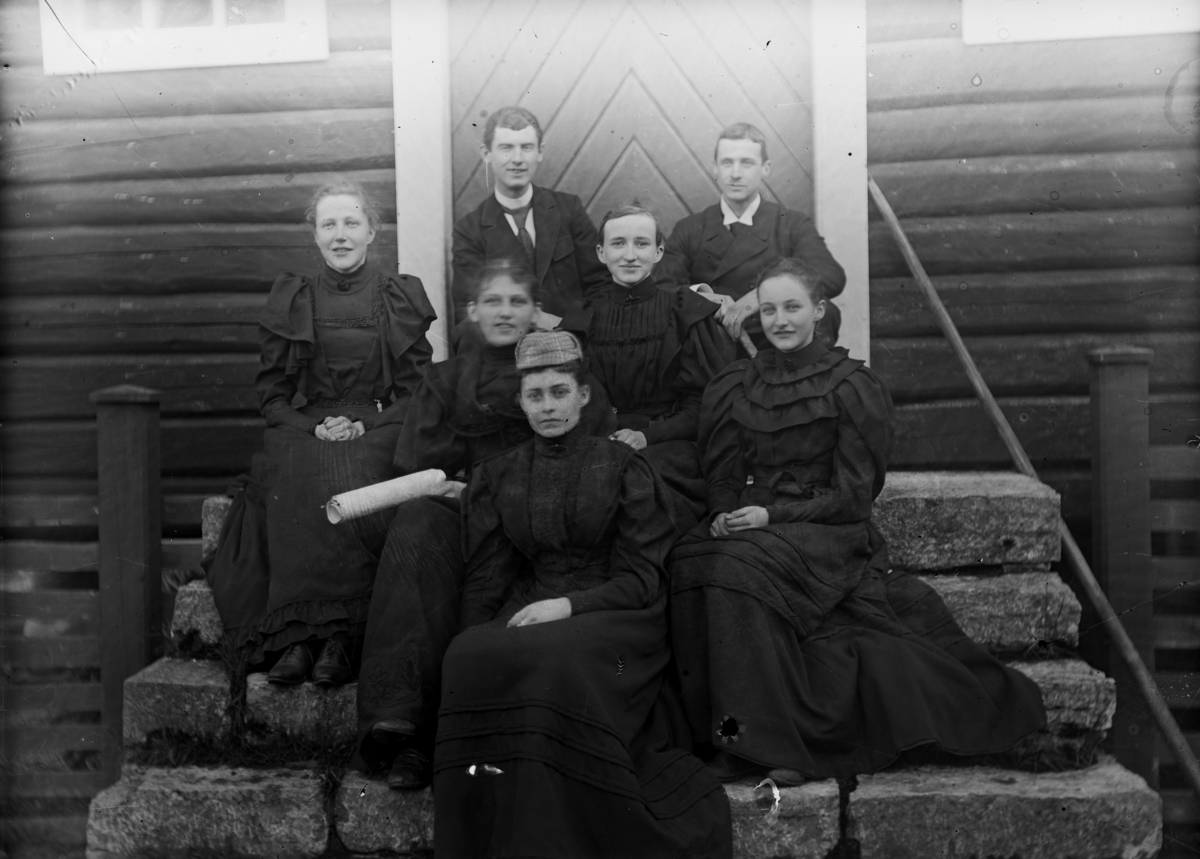 Fem kvinner og to menn på trappa til en bygning. Fremst, ytterst til høyre, sitter Lol Misen (f. Mellbye), fremst sitter Sofie Pihl (f Mellbye). 