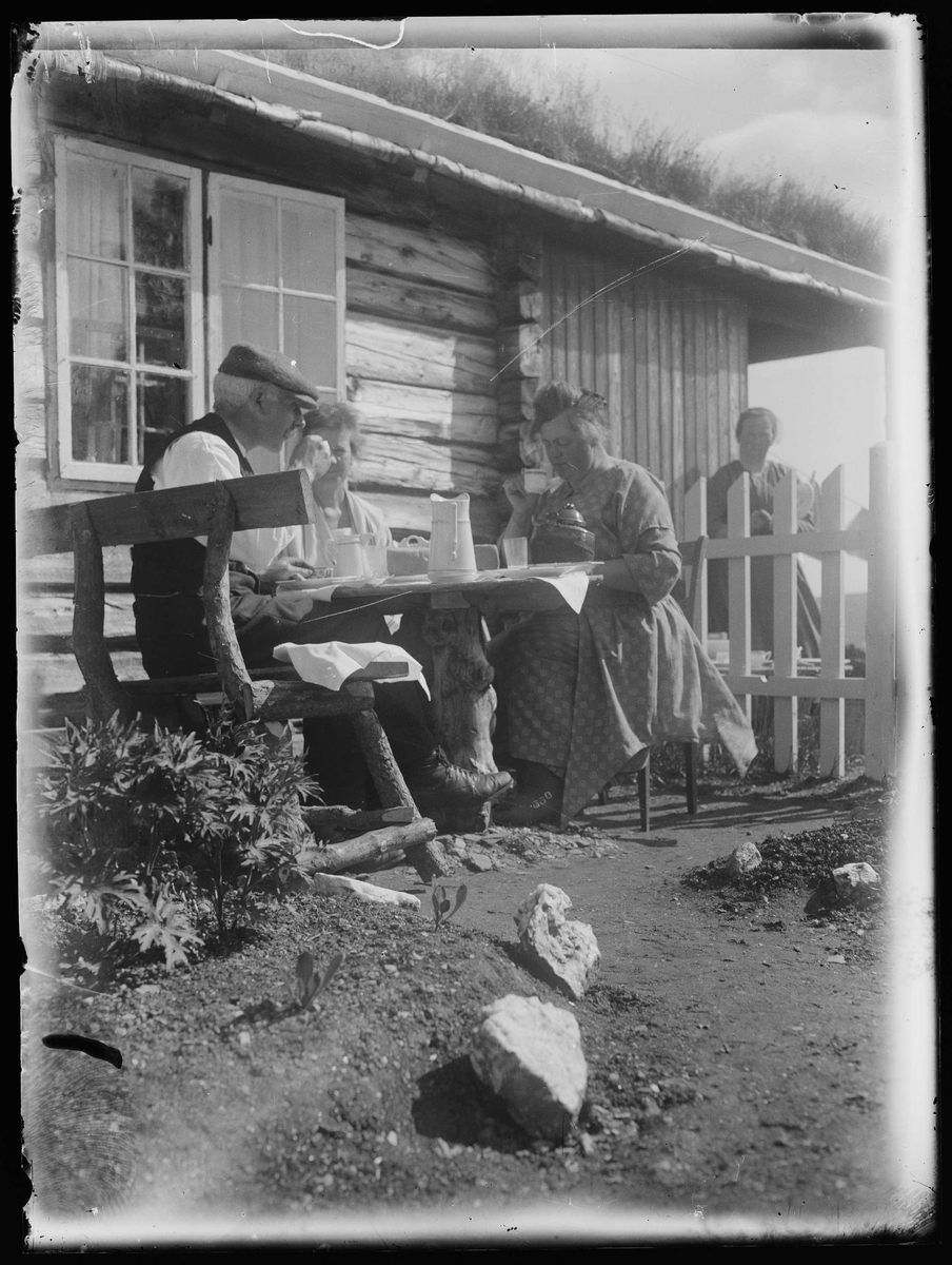 3 personer drikker kaffe i solveggen. Til venstre: fotograf Ole Iversen Buck (1867-1961). Nr fra venstre er Oles kone Helga Buck (1874-1941).