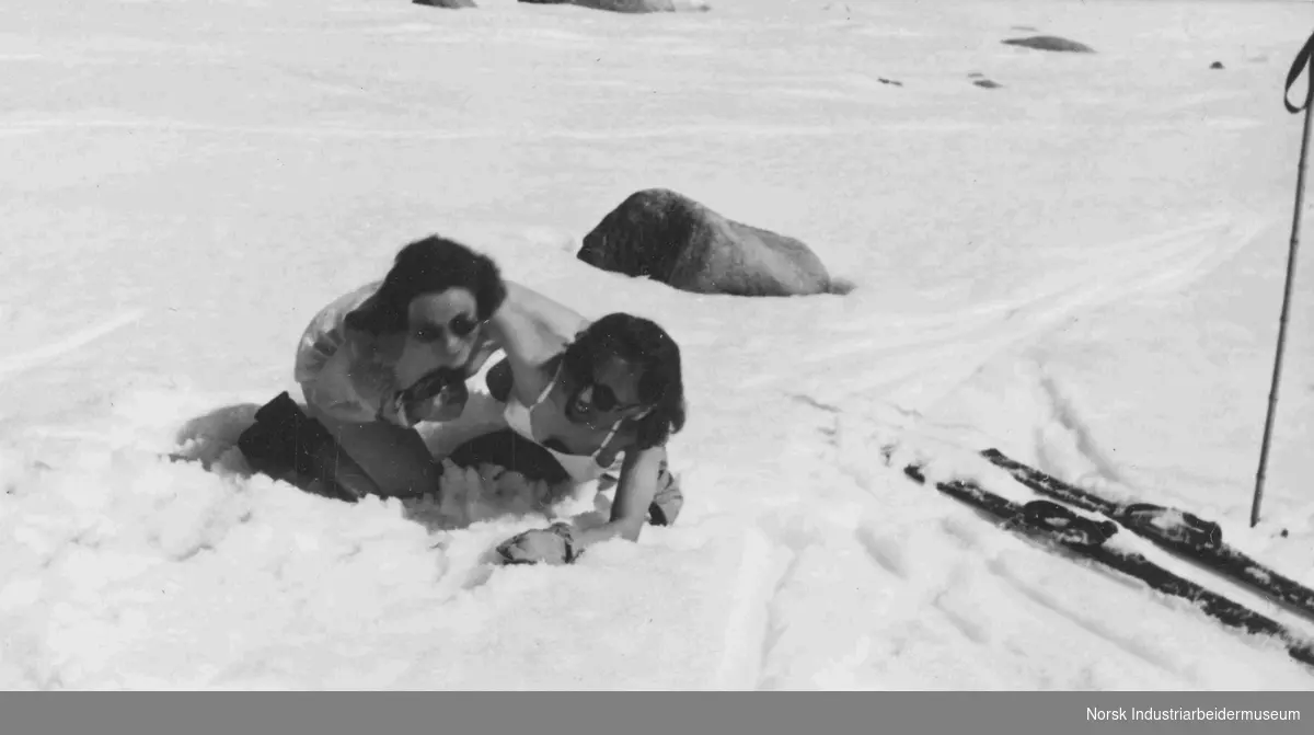 To lettkledte damer lekeslåss i skisporet.  Hedvig Syverstad (t.h.) og Else Getz Hansen (t.v.). Skiene ligger i  bakgrunnen av fotografiet
