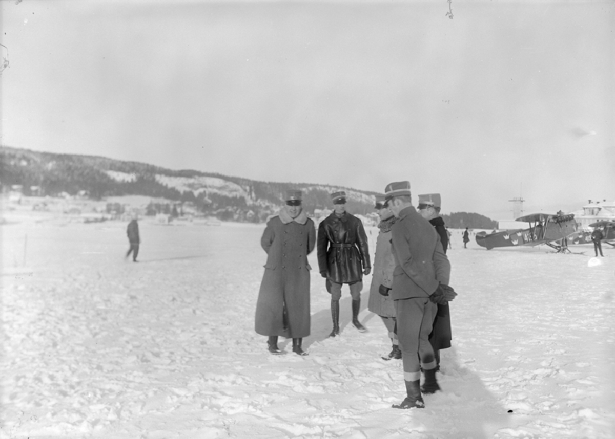 Inspektion på flygstationen i Östersund, vintertid, 1926. Fem män står i en klunga. Flygplan Phönix E1 märkt 4196 i bakgrunden.
