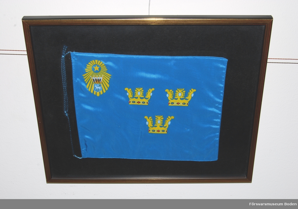 Inramad bordsfana, ljusblå med tre gula öppna kronor i mitten. Övre vänstra hörnet försett med gul stjärna omgiven av strålknippe, vars nedre del innehåller landskapet Västerbottens vapen krönt med hertigkrona. Den ursprungliga fanan överlämnades 1935 av konung Gustaf V.