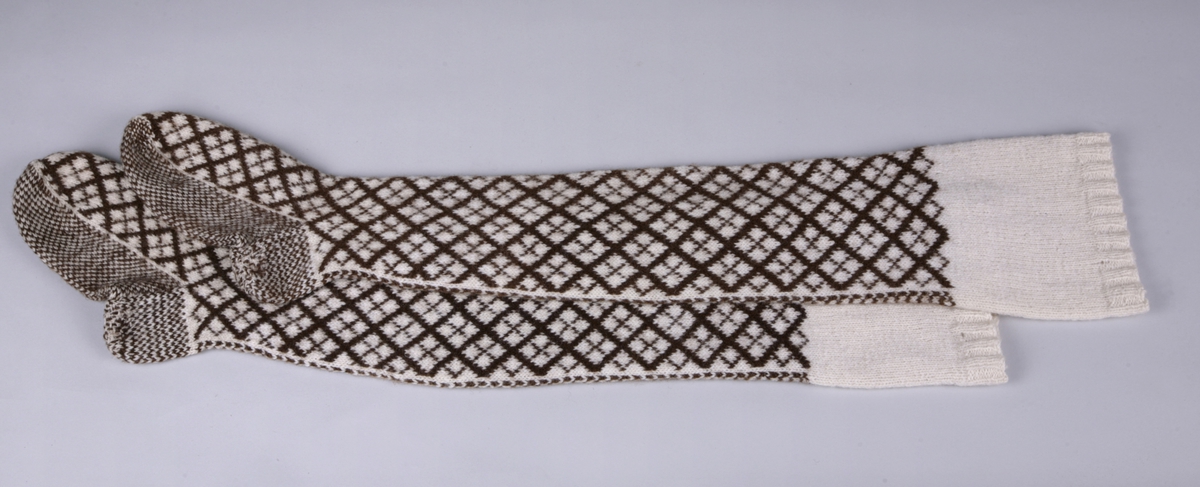 Lange strømper i glatt mønsterstrikk med ribbet kant øverst. Rutete mønsteri hvitt og brunt. Ett par.