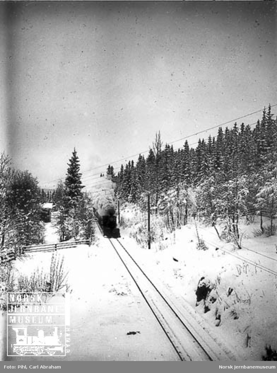 Vinterbilde med damplokomotiv type XVII med stor frontplog foran toget
