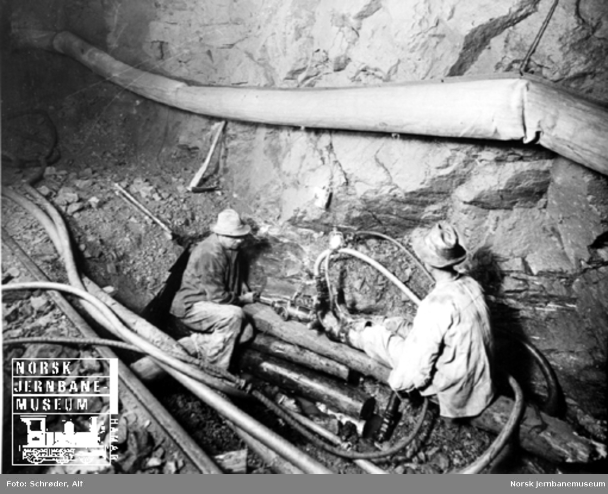 Medjå tunnel : to anleggsarbeidere borer en drensgrøft