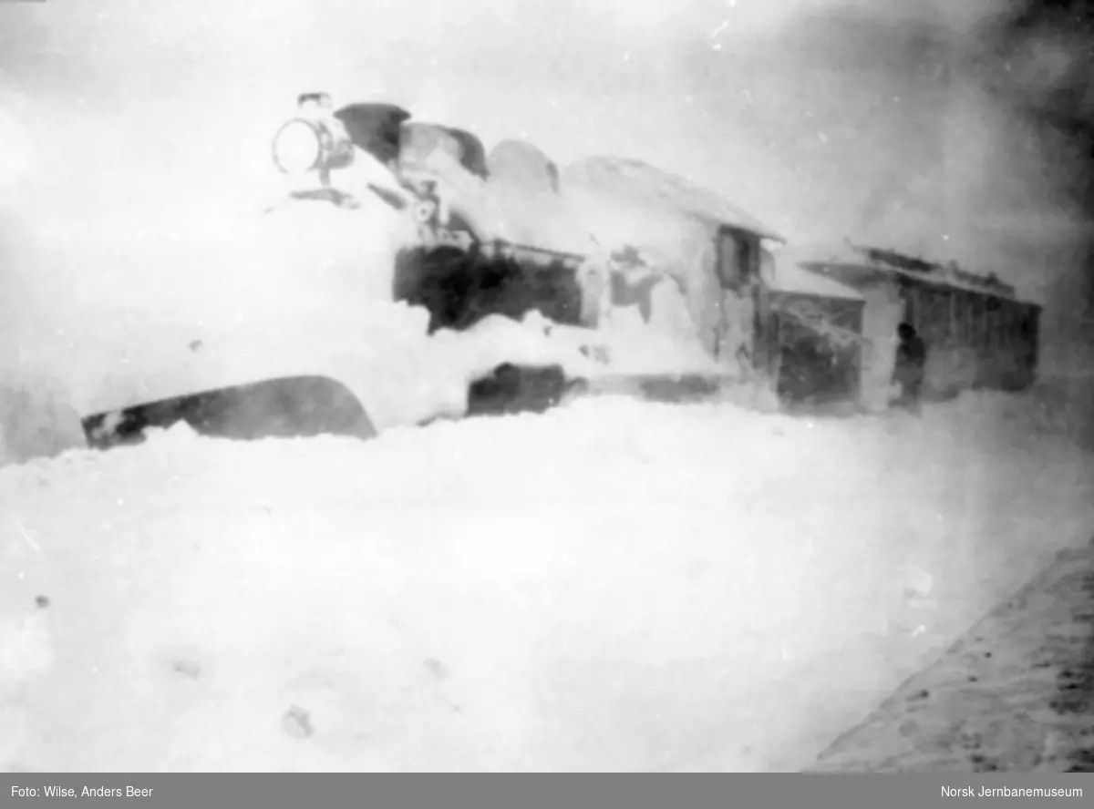 Nedsnødd damplokomotiv type 22a foran en personvogn
