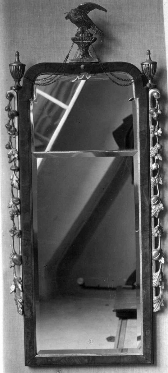 Rektangulært, høyreist speil med 2 speilplater, brun treramme omkranset av forgylt akantus på sidene og ørn med messinglenker sentrert på ovesiden. Treplater på baksiden.