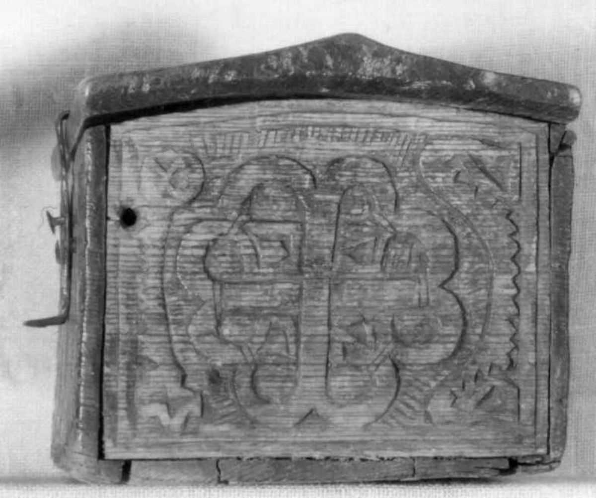 Skrin med flate sider of lett takformet lokk. Hengslet i bakkant og låsmekanisme i forkant. Håndtak midt på lokket. Hele utsidenhar skurd dekor med ranker, dyr og mennesker.