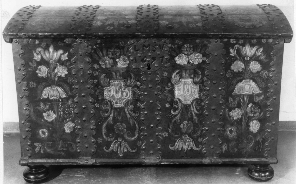 Kiste med buet lokk og heldekkende rosemaling, hvorav mye er senere tilføyelser eller restaureringer. Kulebena er også sekundære.