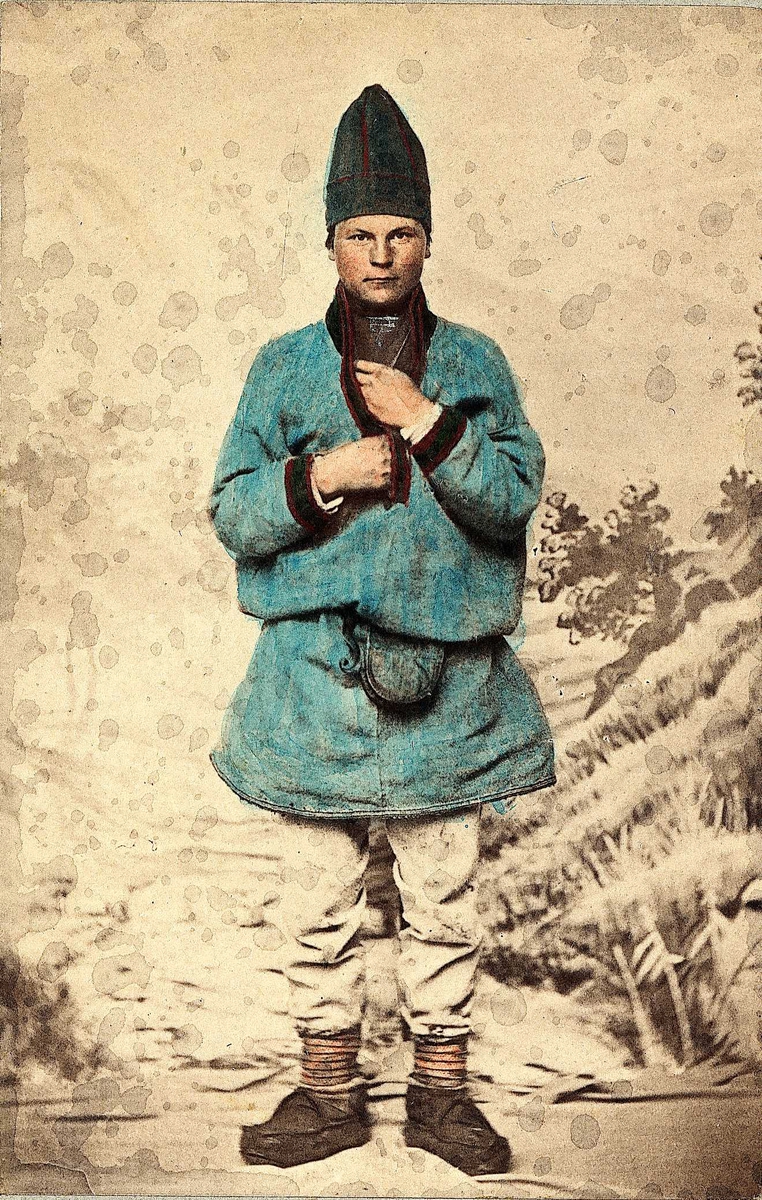 53. Mannsdrakt, samedrakt, Salten. Portrett av mann stående i fotoatelier foran malt naturbakgrunn. 
Fra serien "Norske Nationaldragter" (nr.53) tatt av fotografen Marcus Selmer (1819-1900), Bergen.