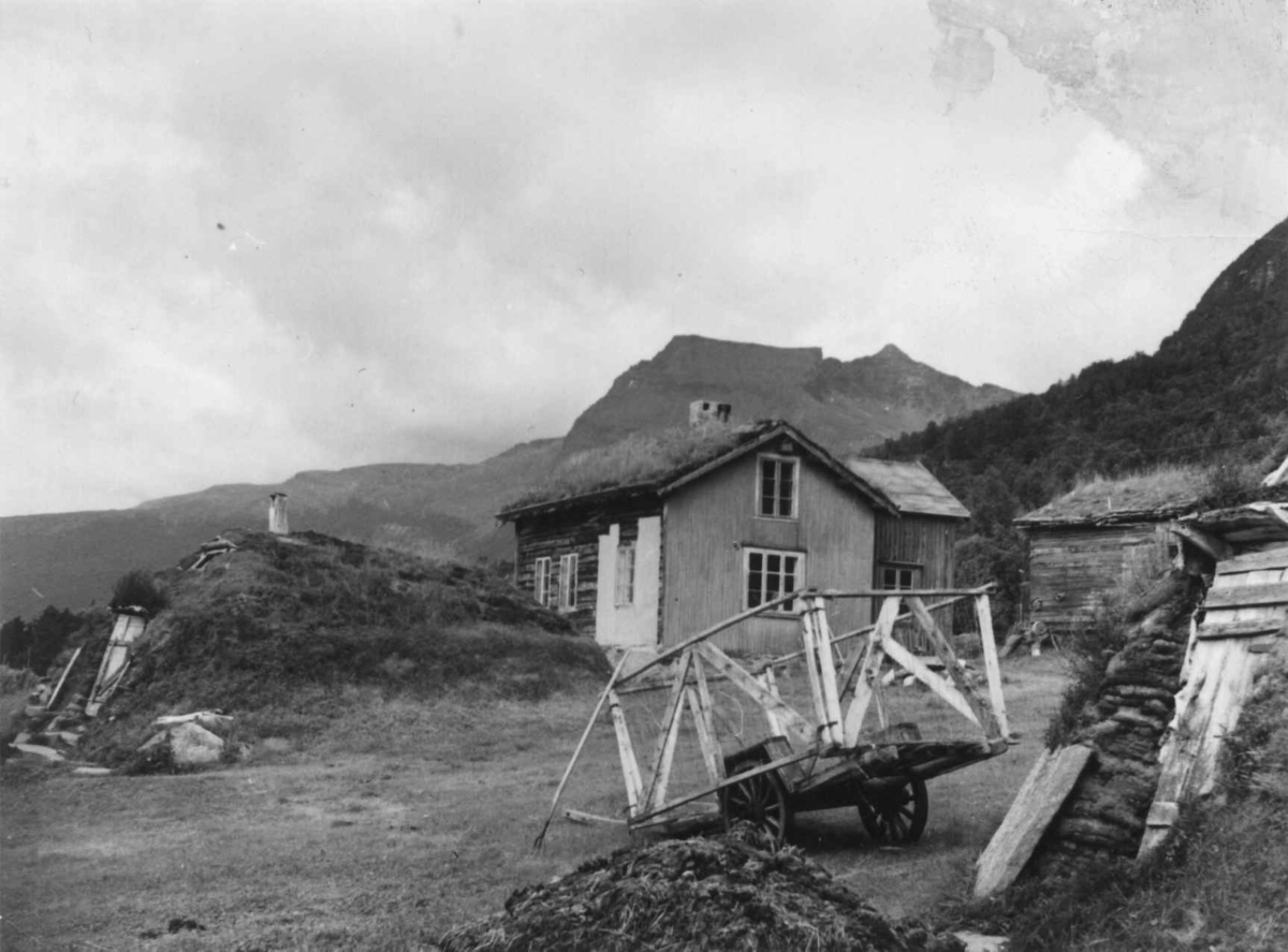 Sjøsamegård i Grovfjord med gamme, uthus og huset til Ole Henriksen, i forgrunnen en kjerre. 1956.