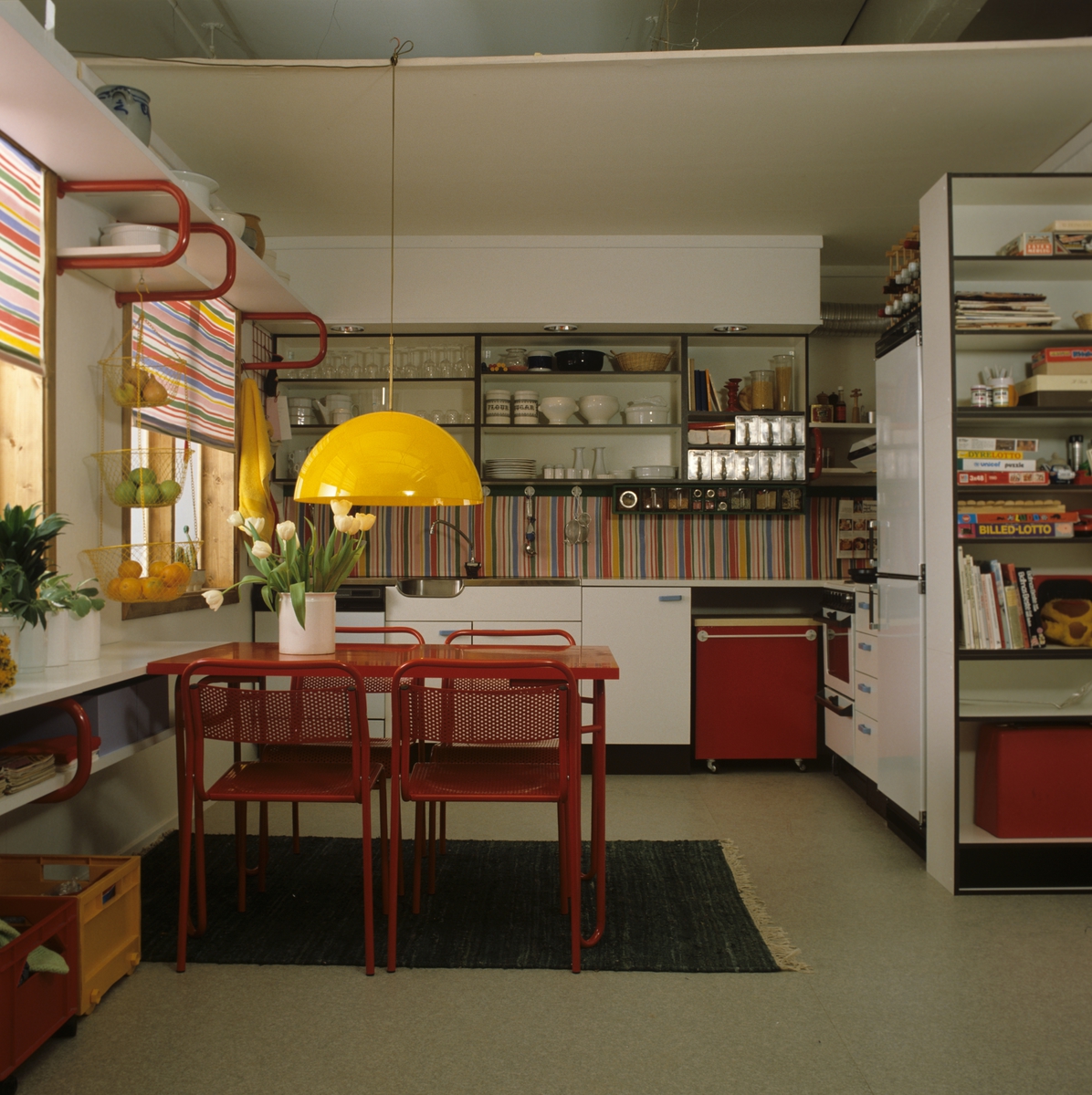 Fargerik kjøkkeninnredning i nybygget boligblokk. Plastbelagt stoff mellom hyller og kjøkkenbenk. Fotografert for Bonytt 1983.