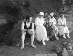 En gruppe mennesker sitter nede ved en strand. Robsahm og Lu
