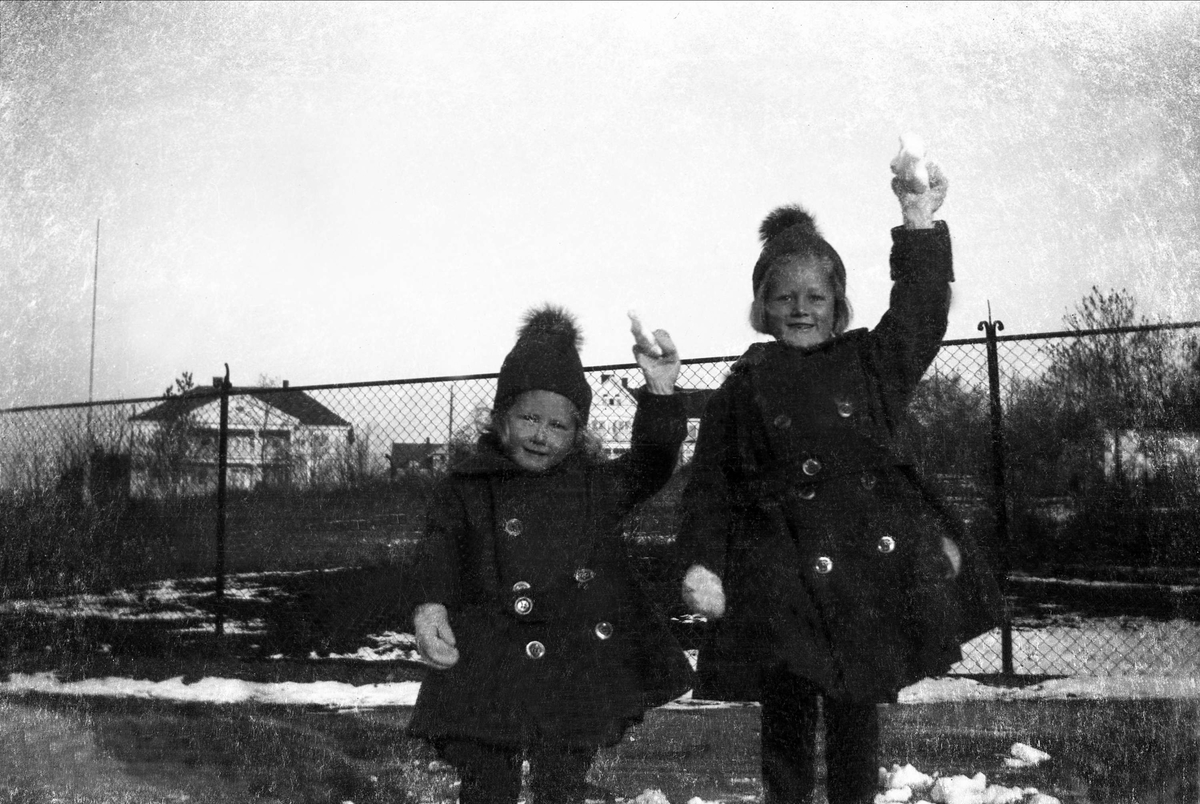 To jenter løfter den ene armen hvor de holder snø i hånden. Robsahm og Lund.