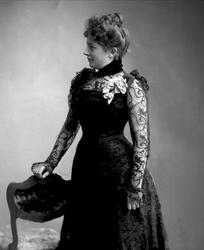 Portrett, kvinne i svart kjole med chiffonermer. Fru Erbe.