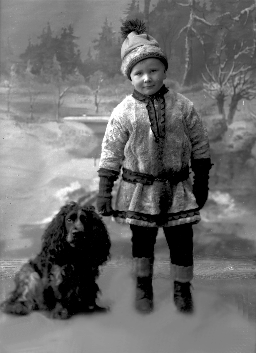 Portrett, liten gutt i samisk inspirert drakt, med hund. Kaptein Zimmers sønn.