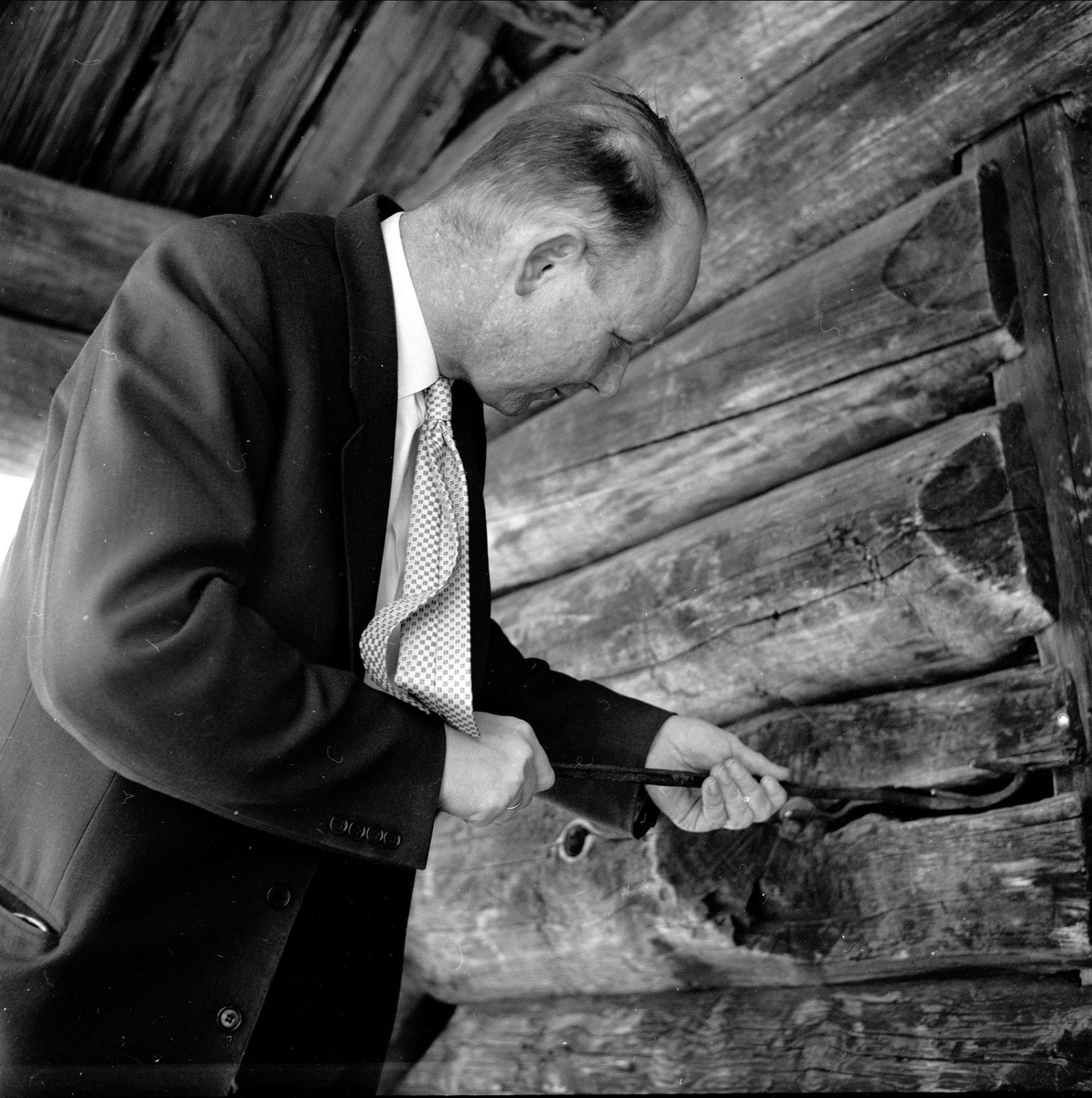Asle Hesla på Oset Høyfjellshotell på Gol i Buskerud 1960. Han står med et redskap i tømmervegg.