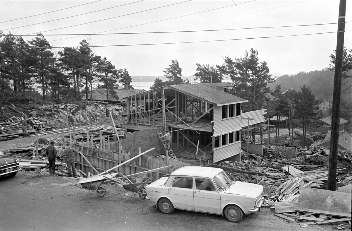 Bilene Simca 1000 og snuten på Morris Oxford 1954-56.
Kristiansand, april 1967. Bil foran et hus under bygging.