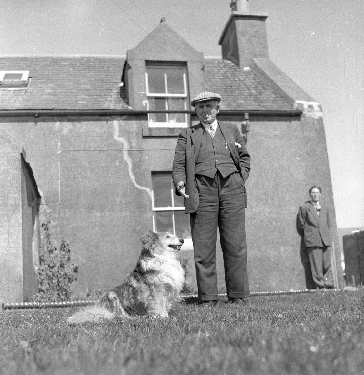 Pigghåfiske på Shetland.
Shetland, 14-22. mai 1958, mann med hund, bebyggelse i bakgrunn.