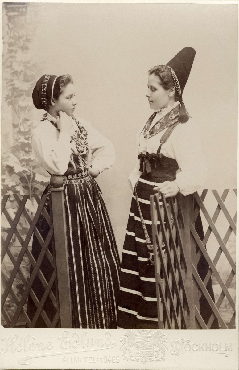 Två unga flickor poserar i folkdräkter, med olika huvudbonad